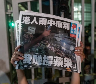 An employee holds up the latest copies of the Apple Daily following its closure on June 24